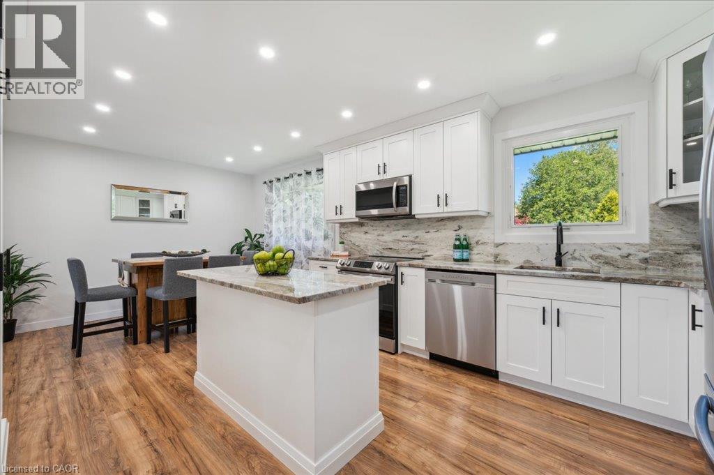 Kitchen featuring white shaker cabinetry, stainless steel appliances, a center island with a stone countertop, and wood-finish flooring - 76 Lower Canada Crescent, Kitchener, ON - Indoor Photo Showing Kitchen With Upgraded Kitchen