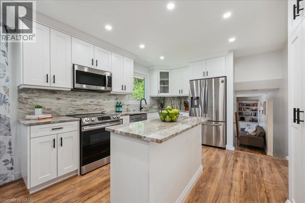 Contemporary kitchen featuring white cabinetry, stainless steel appliances, a center island with stone countertop, wood-finish flooring, and recessed lighting - 76 Lower Canada Crescent, Kitchener, ON - Indoor Photo Showing Kitchen With Upgraded Kitchen