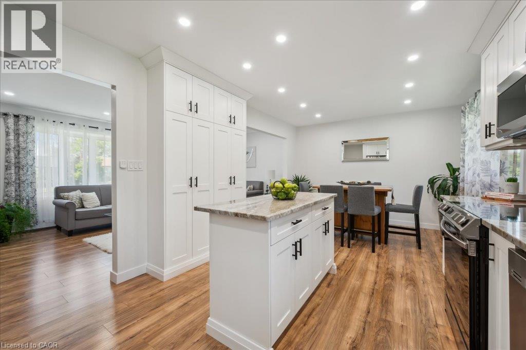 Bright kitchen featuring white shaker cabinetry, stainless steel appliances, a center island with countertop, and wood-finish flooring - 76 Lower Canada Crescent, Kitchener, ON - Indoor Photo Showing Kitchen