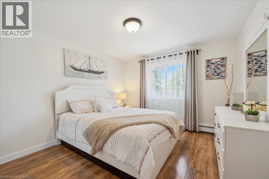 Wood-finish flooring throughout, bright white walls, and a window with sheer and blackout curtains - 76 Lower Canada Crescent, Kitchener, ON - Indoor Photo Showing Bedroom