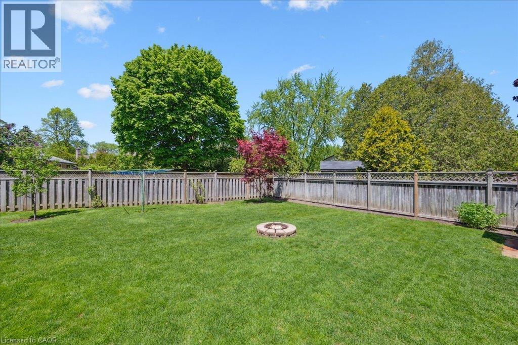 Expansive green lawn with a circular stone fire pit - 76 Lower Canada Crescent, Kitchener, ON - Outdoor With Backyard