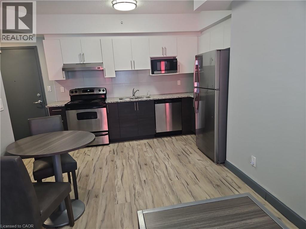Kitchen with appliances with stainless steel finishes, light wood-style flooring, tasteful backsplash, white cabinets, and under cabinet range hood - 258B Sunview Street Unit# 255, Waterloo, ON - Indoor Photo Showing Kitchen With Stainless Steel Kitchen