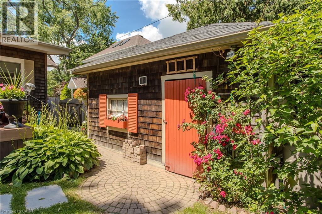 Storage shed with wood shake siding, a vibrant red door, and a window box with red shutters - 569 Locust Street, Burlington, ON - Outdoor With Deck Patio Veranda
