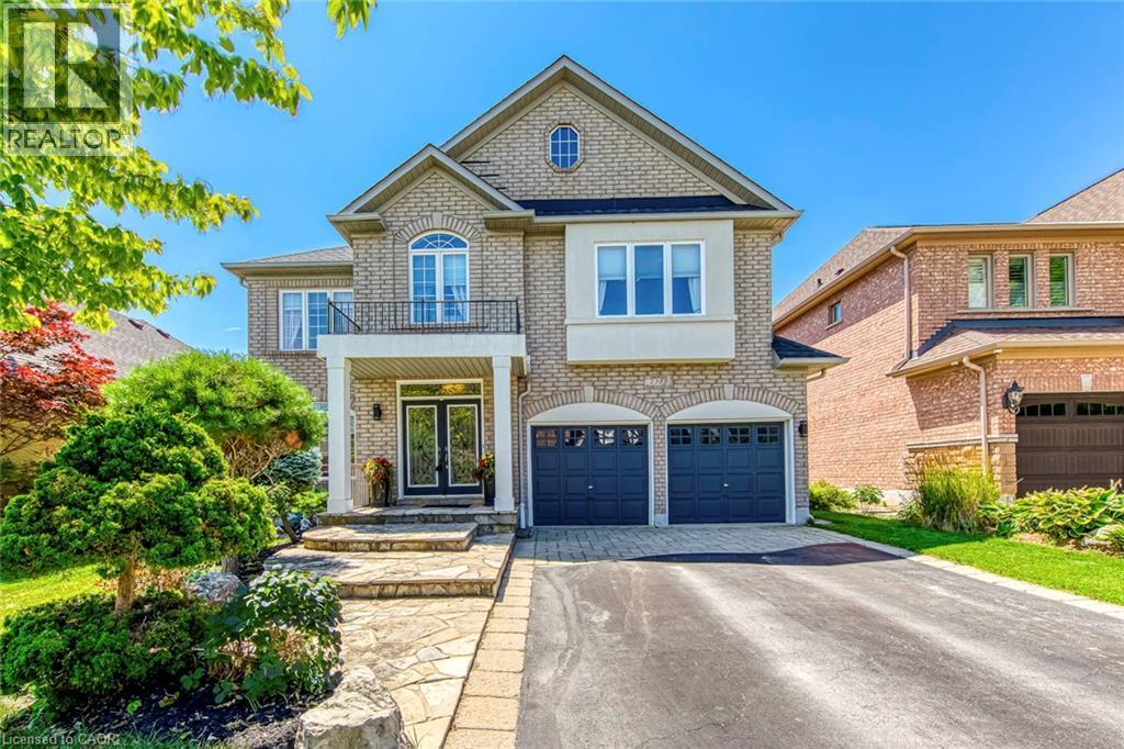 Brick exterior featuring a covered porch entry with double doors, arched garage openings with dark paneled doors, a Juliette balcony, and an arched window dormer - 2380 Woodcrest Drive, Oakville, ON - Outdoor With Facade