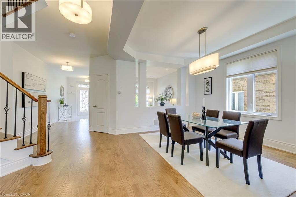 Open-concept dining area featuring wood-finish flooring, a contemporary chandelier, and natural light from a large window - 2380 Woodcrest Drive, Oakville, ON - Indoor Photo Showing Dining Room