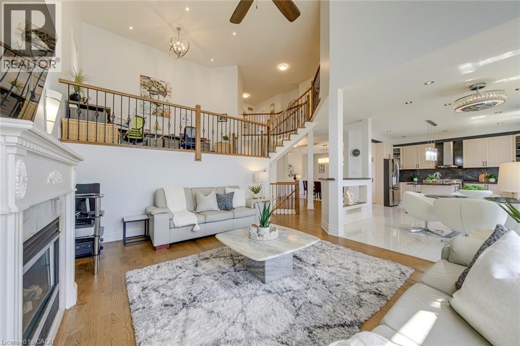 Great room featuring soaring ceilings, a decorative fireplace with an ornate mantel, and wood-finish flooring - 2380 Woodcrest Drive, Oakville, ON - Indoor Photo Showing Other Room With Fireplace