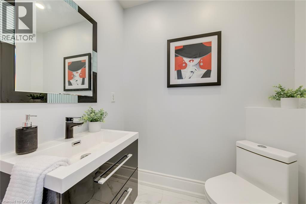 Modern vanity featuring a rectangular integrated sink, a matte black faucet, and sleek black cabinetry with chrome hardware - 2380 Woodcrest Drive, Oakville, ON - Indoor Photo Showing Bathroom
