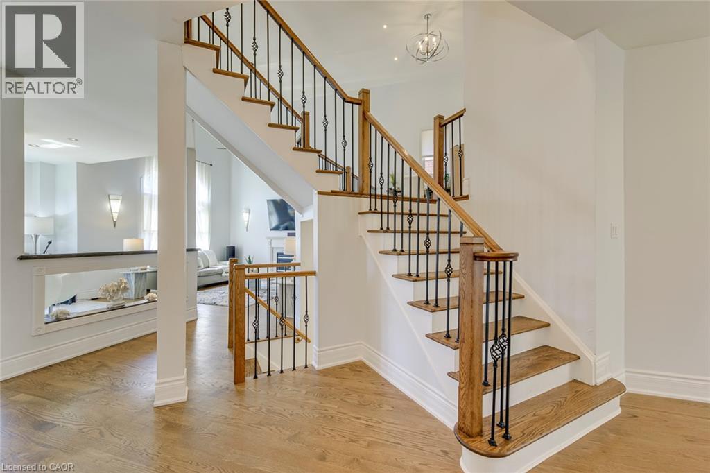Hardwood flooring throughout the entry, featuring a custom staircase with wrought iron spindles and wood handrails - 2380 Woodcrest Drive, Oakville, ON - Indoor Photo Showing Other Room