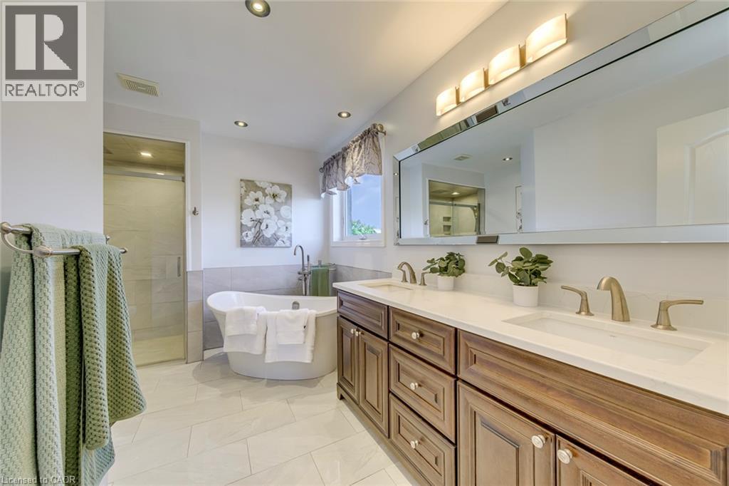 Bathroom featuring a dual vanity with wood-finish cabinetry, white countertop, and brushed nickel fixtures - 2380 Woodcrest Drive, Oakville, ON - Indoor Photo Showing Bathroom