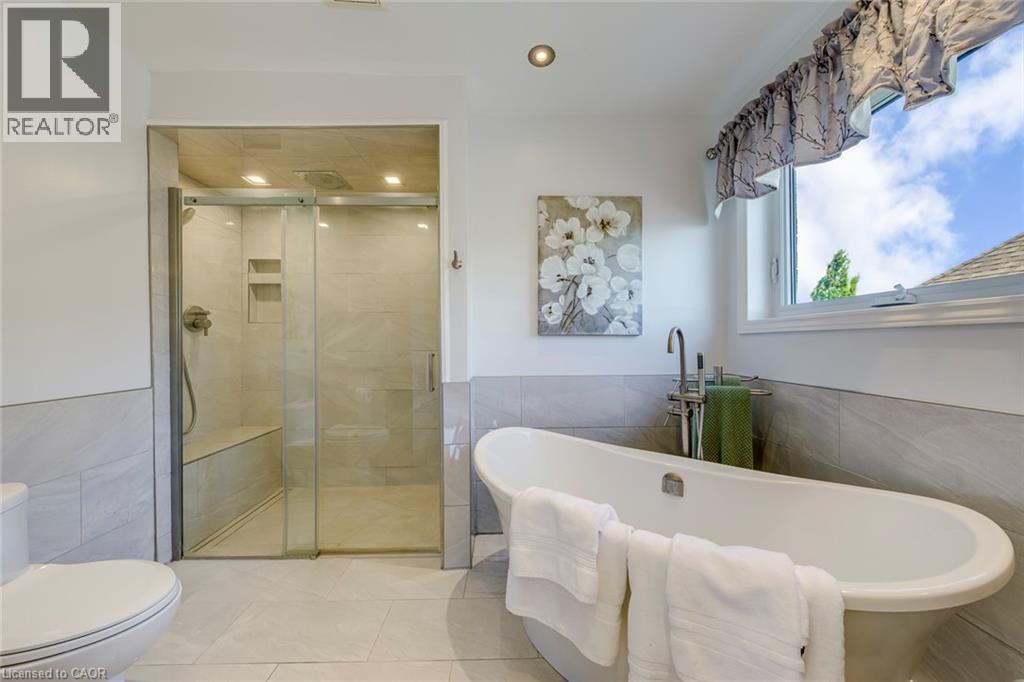 Bathroom featuring a freestanding soaking tub, a walk-in shower with a built-in bench, and a large window - 2380 Woodcrest Drive, Oakville, ON - Indoor Photo Showing Bathroom