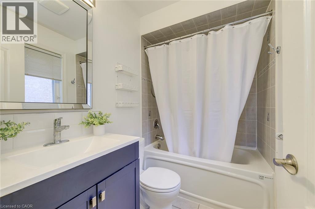 Bathroom featuring a vanity with a dark blue cabinet and white countertop, chrome faucet, and a framed mirror - 2380 Woodcrest Drive, Oakville, ON - Indoor Photo Showing Bathroom