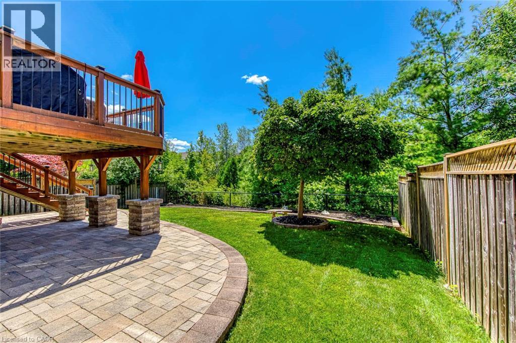 Spacious backyard featuring a paver patio with decorative stone pillars, a manicured lawn, and a mature tree - 2380 Woodcrest Drive, Oakville, ON - Outdoor