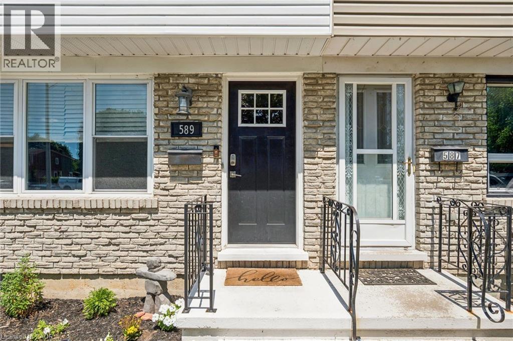 Stone veneer facade featuring a black paneled door with window inserts, white window frames, and decorative wrought iron railings - 589 Elgin Street N, Cambridge, ON - Outdoor