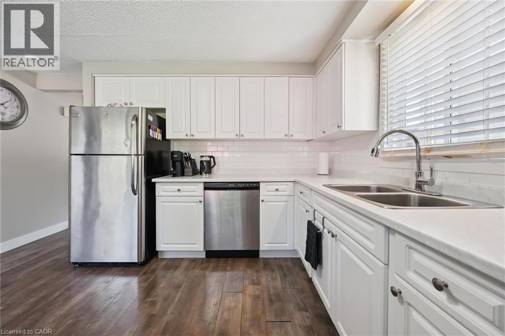 Kitchen featuring white cabinetry with hardware, wood-finish flooring, and white countertops - 589 Elgin Street N, Cambridge, ON - Indoor Photo Showing Kitchen With Double Sink
