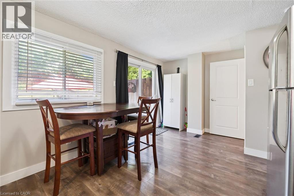 Bright dining area featuring wood-finish flooring, a large window with blinds, and a sliding glass door - 589 Elgin Street N, Cambridge, ON - Indoor Photo Showing Dining Room