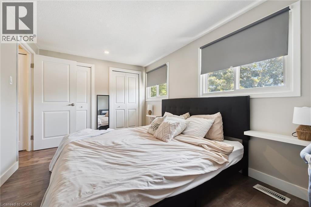 Spacious room featuring wood-finish flooring, two large windows with roller shades, recessed lighting, and ample closet space with bi-fold doors - 589 Elgin Street N, Cambridge, ON - Indoor Photo Showing Bedroom
