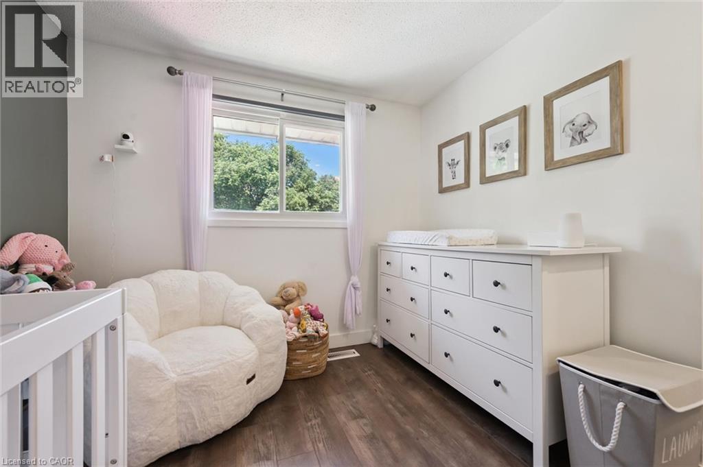 Room with wood-finish flooring, a white trim window, and white walls complemented by an accent wall - 589 Elgin Street N, Cambridge, ON - Indoor Photo Showing Bedroom
