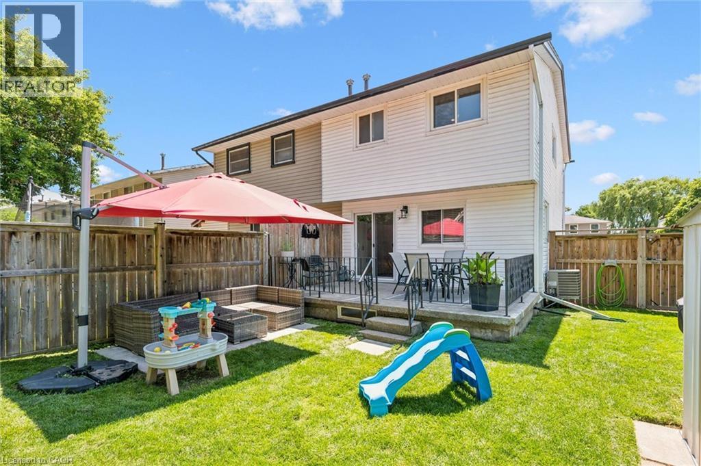 Fenced backyard featuring a raised deck with patio space, established lawn, and wooden privacy fencing - 589 Elgin Street N, Cambridge, ON - Outdoor