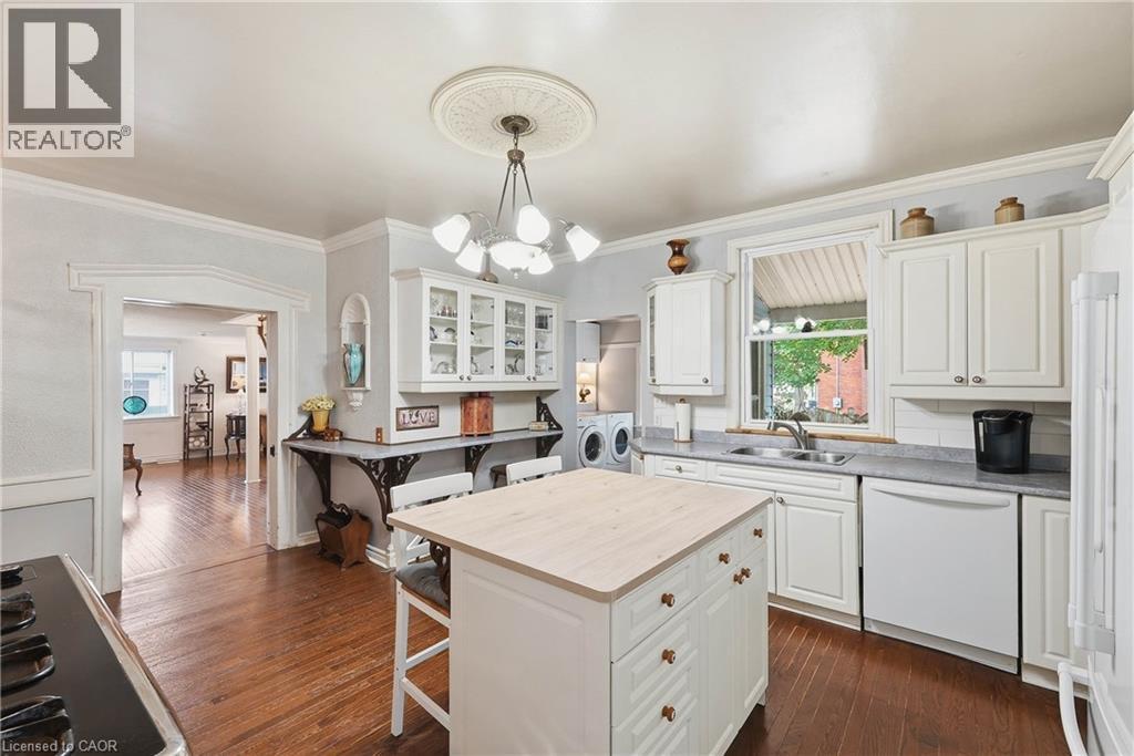 Kitchen featuring white cabinetry, wood-finish flooring, a central island with storage, double-basin sink, and recessed appliances - 153 Montrose Street N, Cambridge, ON - Indoor Photo Showing Kitchen With Double Sink