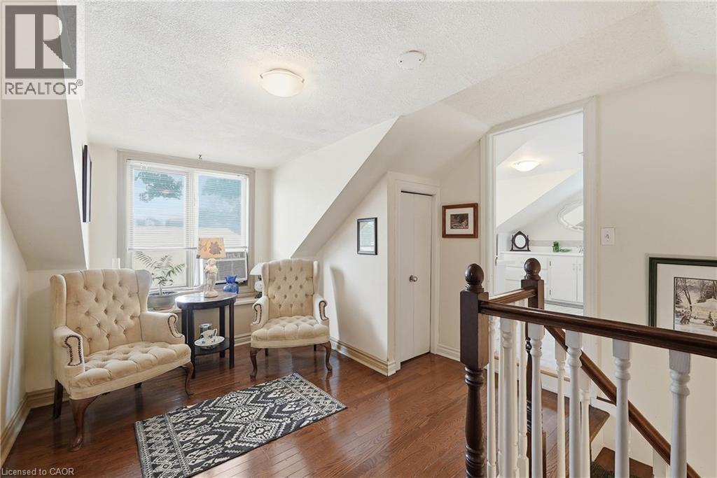 Upper-level landing featuring wood-finish flooring, a double window, and an adjacent room with white cabinetry - 153 Montrose Street N, Cambridge, ON - Indoor Photo Showing Other Room