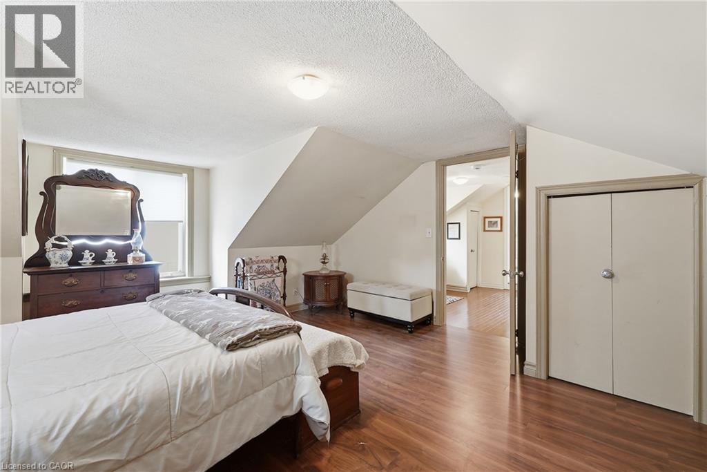 Sloped ceilings with a textured finish, wood-finish flooring, and a window with roller shade - 153 Montrose Street N, Cambridge, ON - Indoor Photo Showing Bedroom