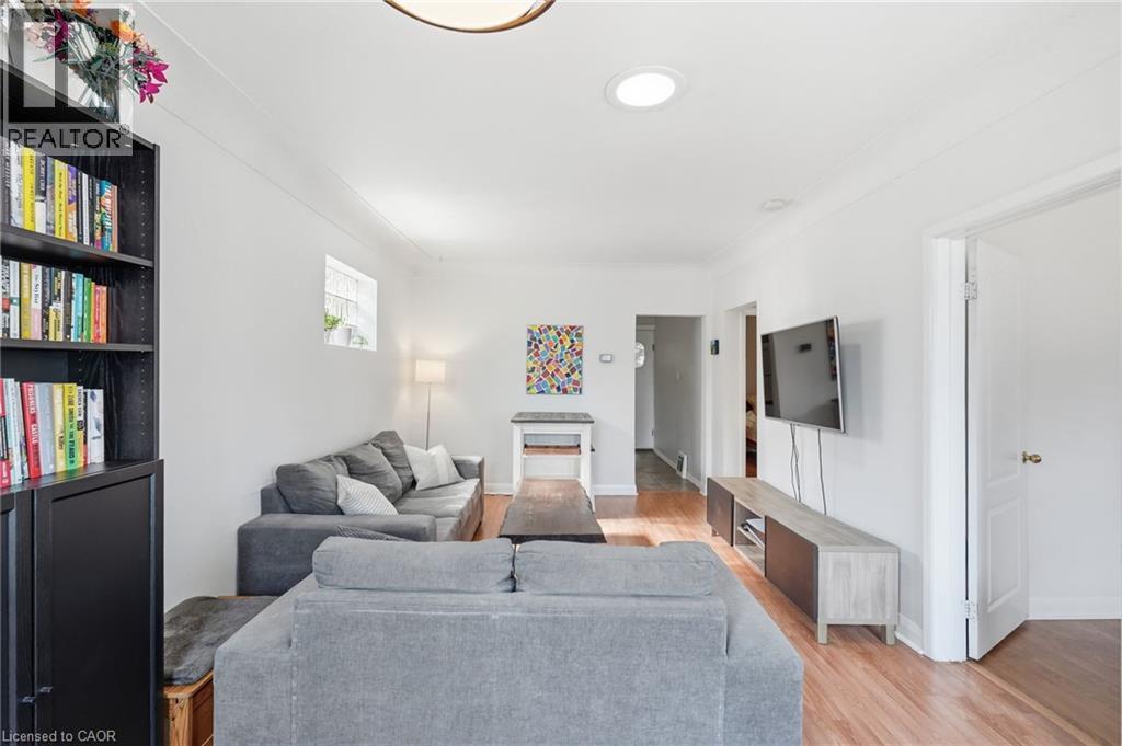Spacious living area featuring light wood-finish flooring, white walls, and crown molding - 58 Edinburgh Avenue, Hamilton, ON - Indoor Photo Showing Other Room