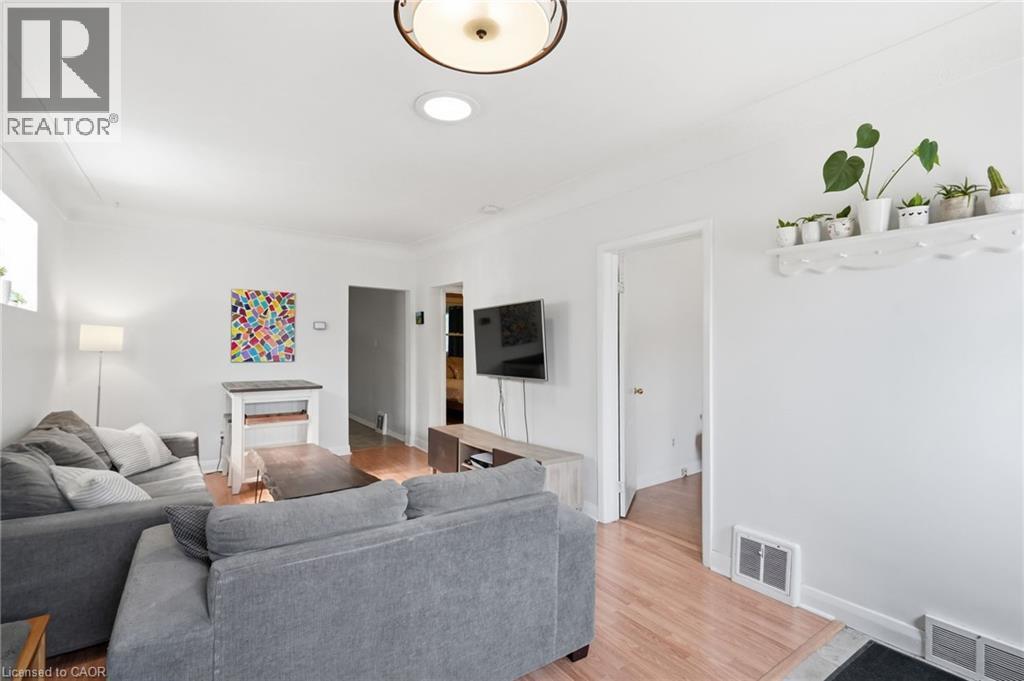 Open concept living space featuring wood-finish flooring, recessed lighting, and a prominent ceiling light fixture - 58 Edinburgh Avenue, Hamilton, ON - Indoor Photo Showing Living Room