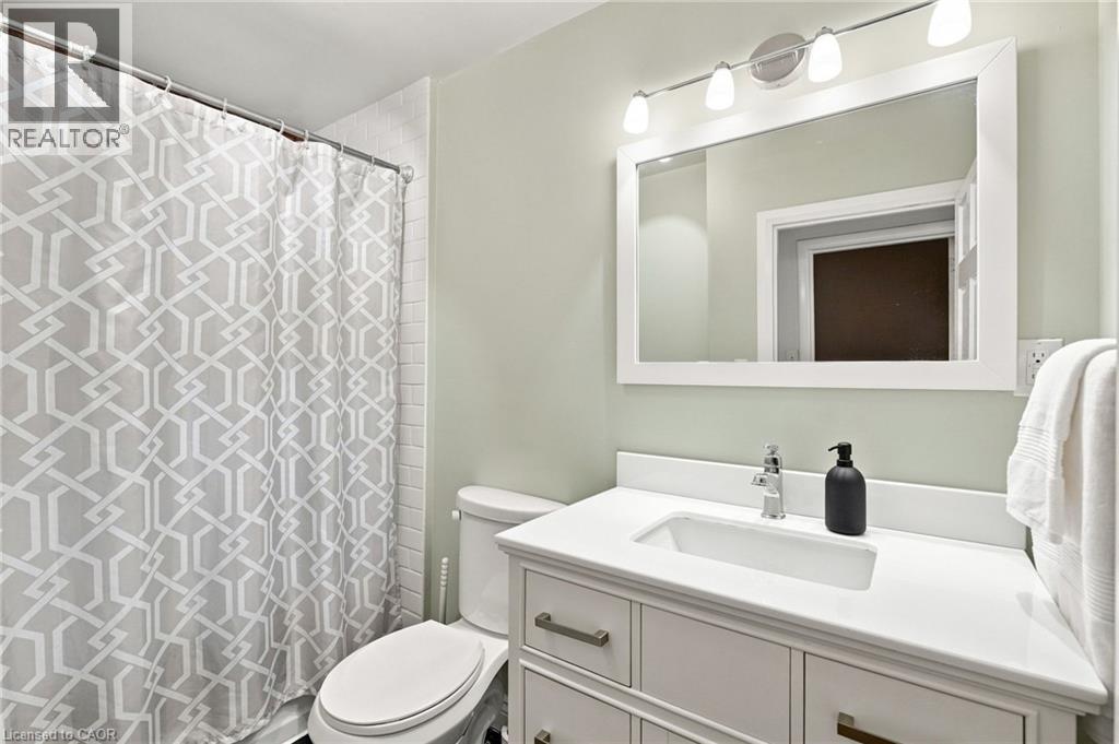 Bathroom featuring a white vanity with integrated sink, chrome faucet, white framed mirror, and a four-light fixture - 58 Edinburgh Avenue, Hamilton, ON - Indoor Photo Showing Bathroom