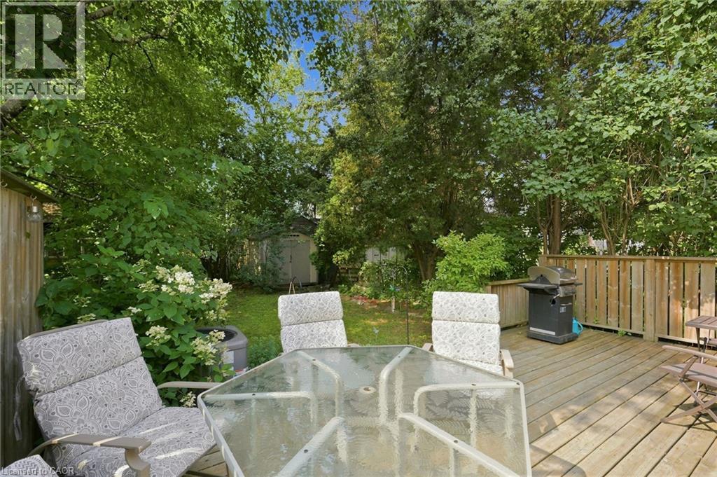 Expansive wooden deck with a privacy fence, overlooking a lush green lawn, mature trees, and a storage shed - 58 Edinburgh Avenue, Hamilton, ON - Outdoor With Deck Patio Veranda