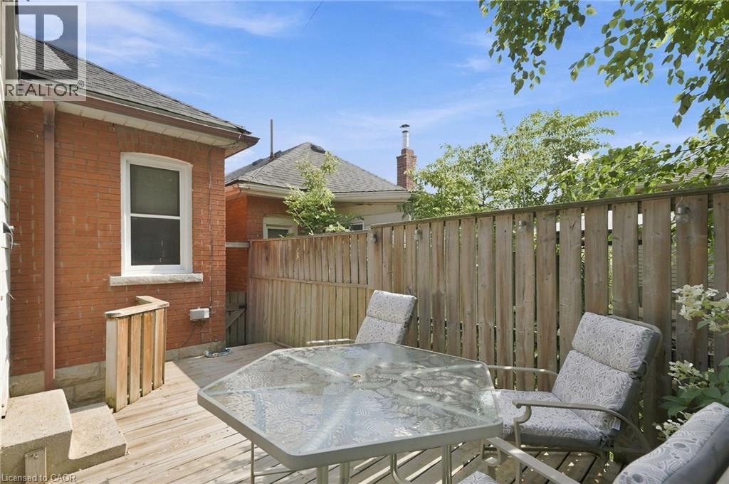Wood-finish deck with a privacy fence, featuring a red brick exterior and a white-trimmed window - 58 Edinburgh Avenue, Hamilton, ON - Outdoor With Deck Patio Veranda With Exterior