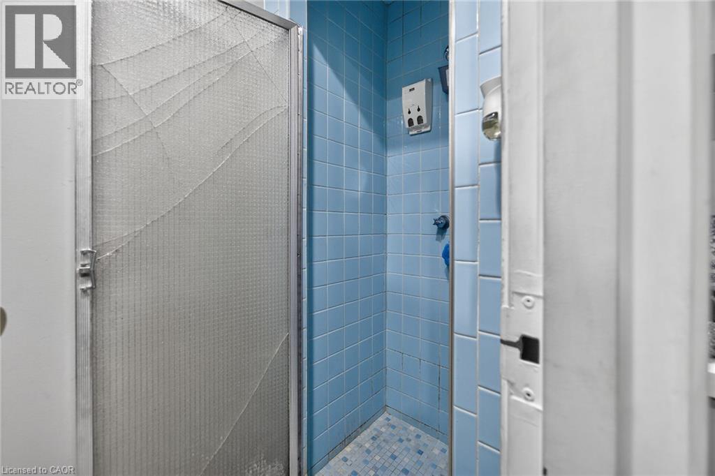 Shower enclosure with blue wall tiles and a patterned tile floor - 1292 Barton Street E, Hamilton, ON