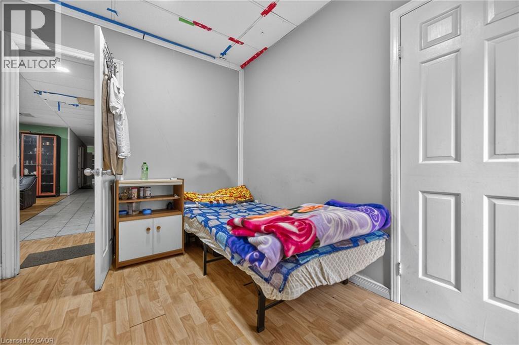 Room featuring light gray painted walls, wood-finish flooring, and a white paneled door - 1292 Barton Street E, Hamilton, ON