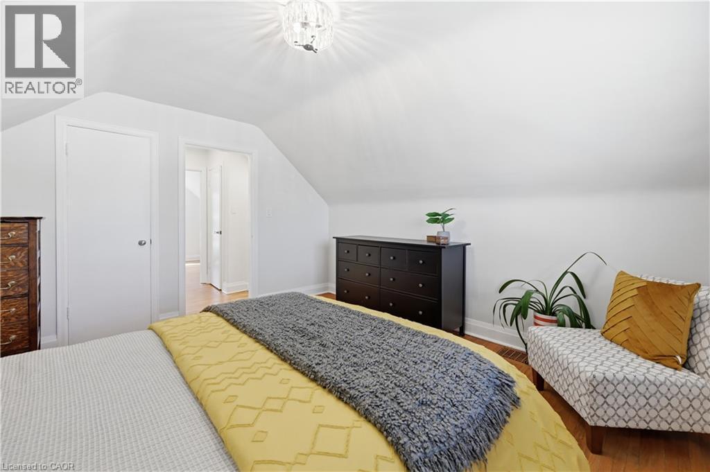 Attic space featuring sloped ceilings, hardwood flooring, recessed entry, and a contemporary ceiling light fixture - 18 Ipswich Place, Hamilton, ON - Indoor Photo Showing Bedroom