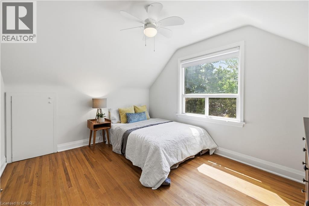 Room featuring wood-finish flooring, a white ceiling fan with integrated lighting, a single window with white trim, and white painted walls - 18 Ipswich Place, Hamilton, ON - Indoor Photo Showing Bedroom