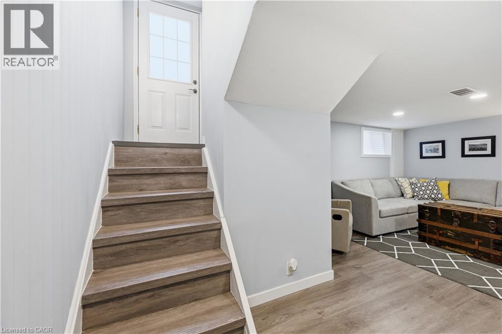 Finished lower level featuring wood-finish flooring, recessed lighting, and a white egress window - 18 Ipswich Place, Hamilton, ON - Indoor