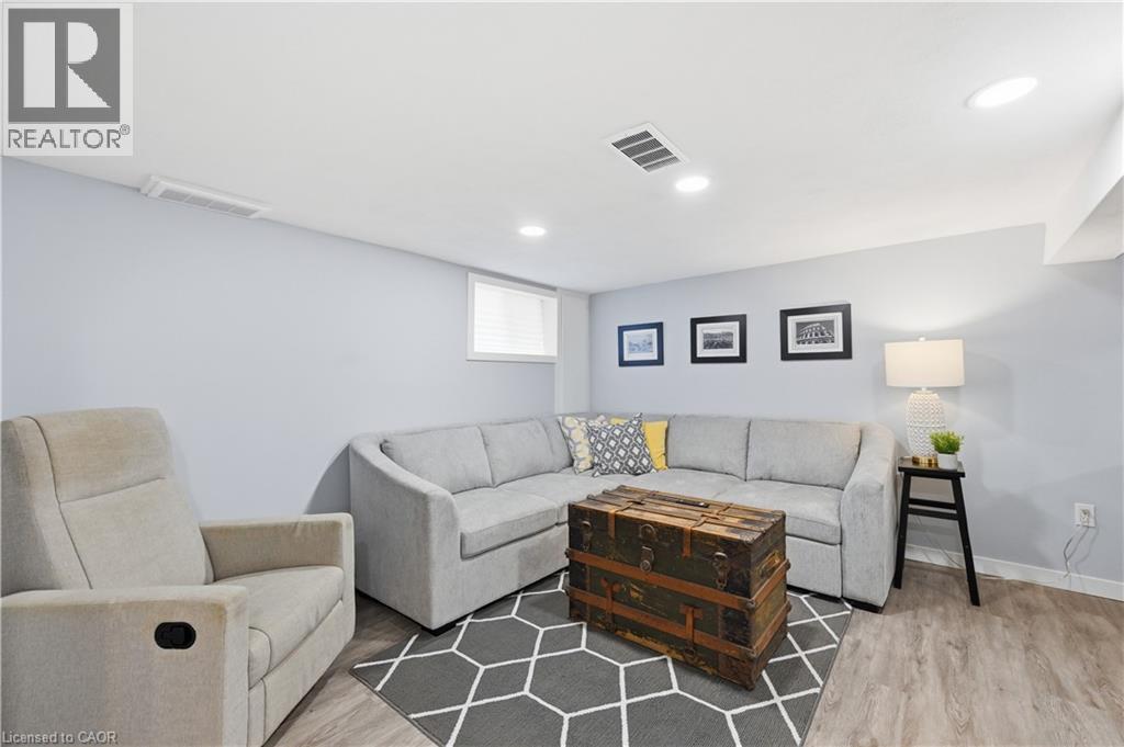 Spacious room featuring light blue walls, recessed lighting, white trim, wood-finish flooring, and a window with blinds - 18 Ipswich Place, Hamilton, ON - Indoor