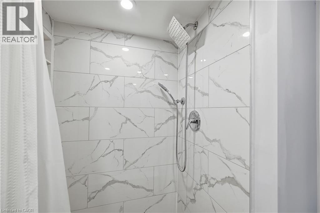 Shower with white veined tile surround, rain shower head, handheld shower fixture, and polished chrome hardware - 18 Ipswich Place, Hamilton, ON - Indoor Photo Showing Bathroom