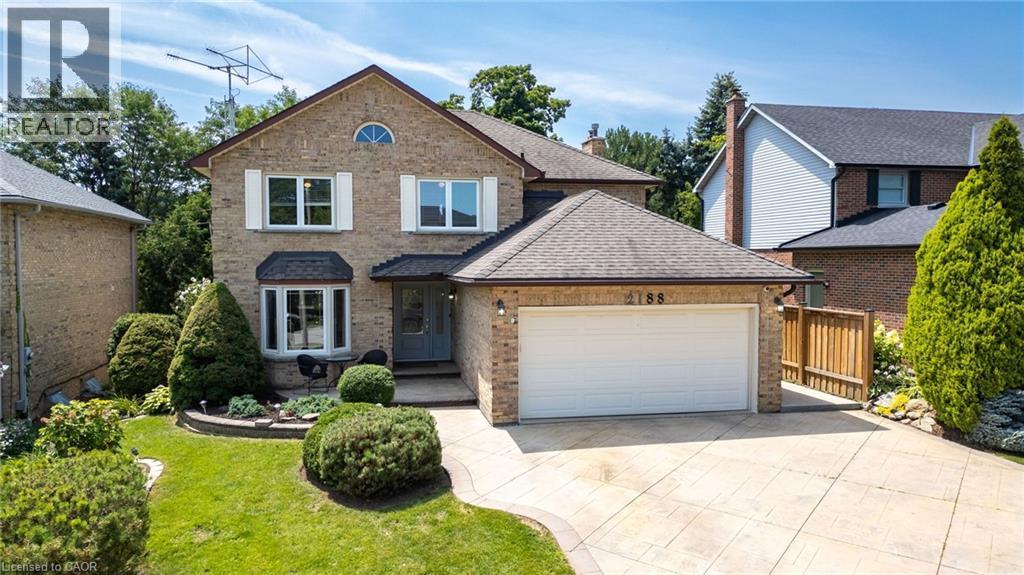 Two-story brick facade residence featuring a two-car garage, bay window, and gabled roofline - 2188 Bader Crescent, Burlington, ON - Outdoor With Facade