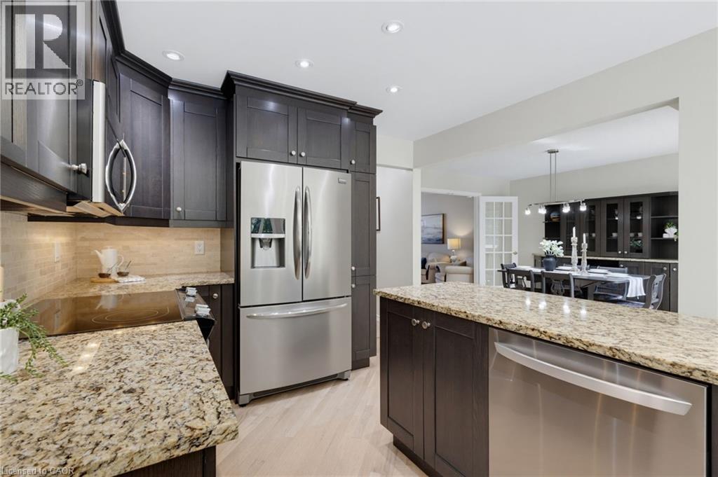Kitchen featuring rich wood cabinetry, stainless steel appliances, granite countertops, and a tiled backsplash - 2188 Bader Crescent, Burlington, ON - Indoor Photo Showing Kitchen With Stainless Steel Kitchen With Upgraded Kitchen