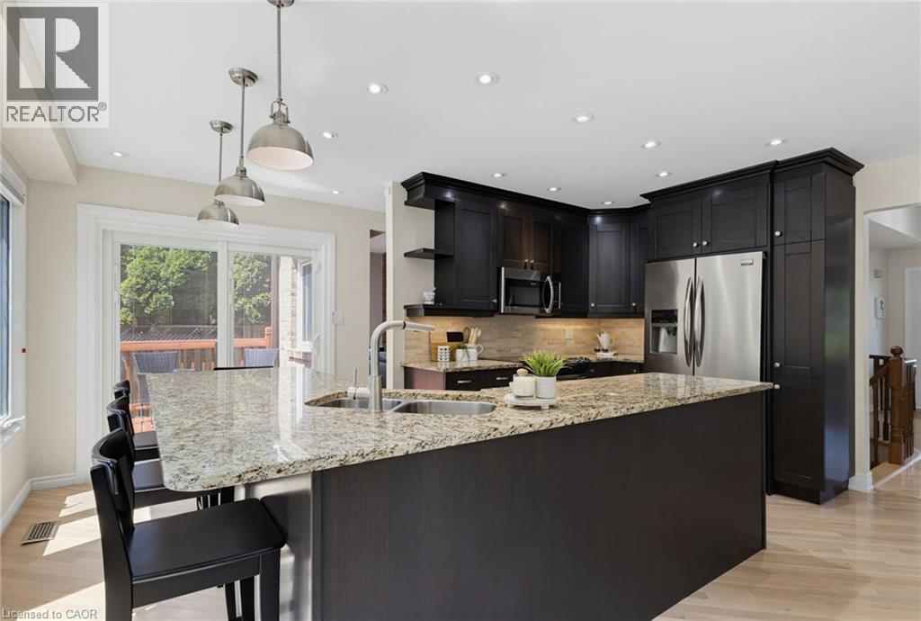 Modern kitchen featuring a granite-topped island with an under mount sink and ample seating. - 2188 Bader Crescent, Burlington, ON - Indoor Photo Showing Kitchen With Stainless Steel Kitchen With Double Sink With Upgraded Kitchen
