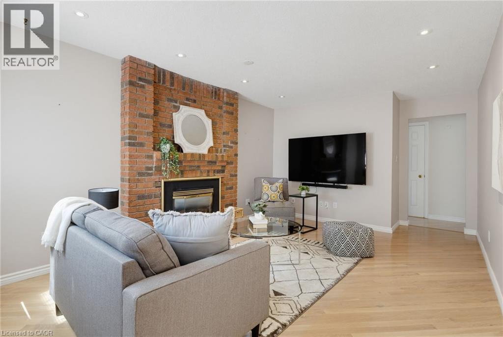 Living area featuring a brick accent wall with a gas insert fireplace, recessed lighting, wood-finish flooring, and light-toned wall paint - 2188 Bader Crescent, Burlington, ON - Indoor Photo Showing Living Room With Fireplace