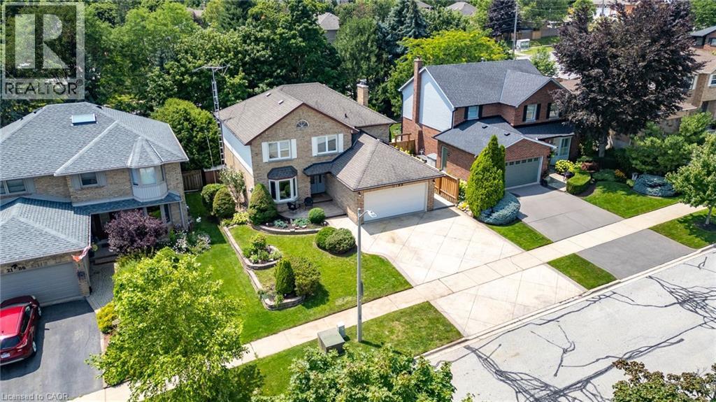 Brick two-story residence featuring a bay window, attached garage, and landscaped front yard with mature shrubbery - 2188 Bader Crescent, Burlington, ON - Outdoor With Facade