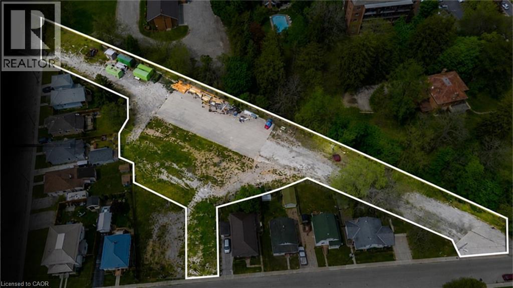 Expansive undeveloped land parcel outlined in white, featuring a substantial gravel area and bordering a wooded hillside - 9 James Street, Simcoe, ON