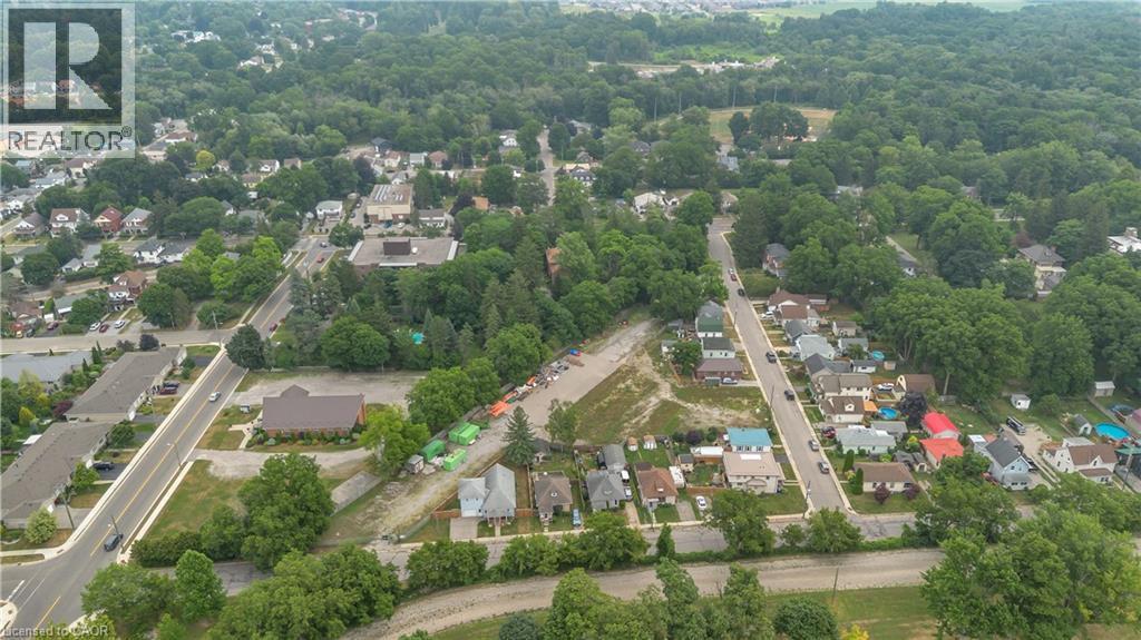 Aerial perspective showcasing a residential area with mature tree canopies, multiple streets, and varied property types - 9 James Street, Simcoe, ON