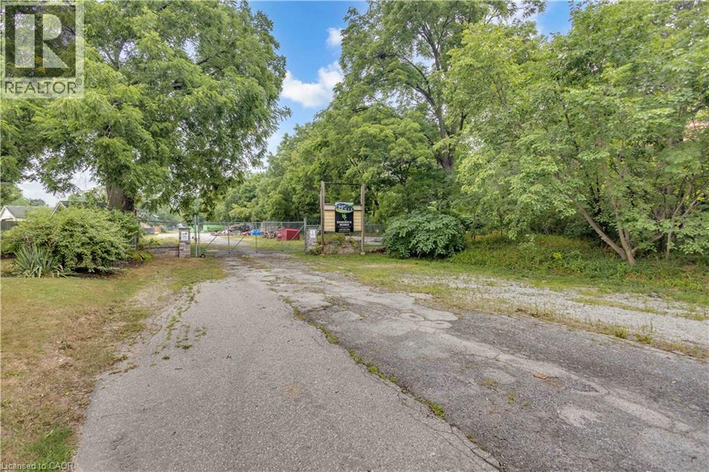 Gated entry with chain-link fencing, mature trees, and natural landscaping - 9 James Street, Simcoe, ON