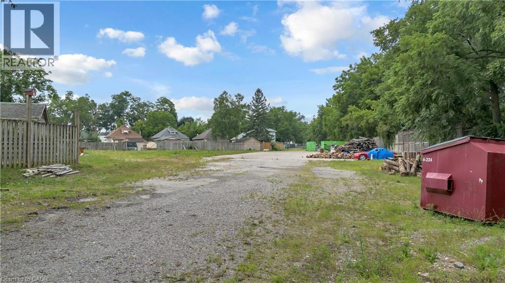 Expansive gravel lot with surrounding mature trees and partial fencing - 9 James Street, Simcoe, ON