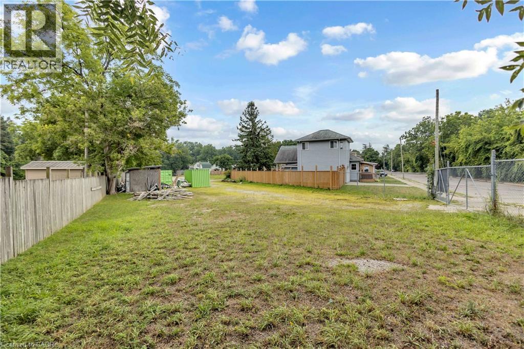 Expansive lot featuring a chain-link fence at the property entrance and a wood privacy fence along the perimeter - 9 James Street, Simcoe, ON