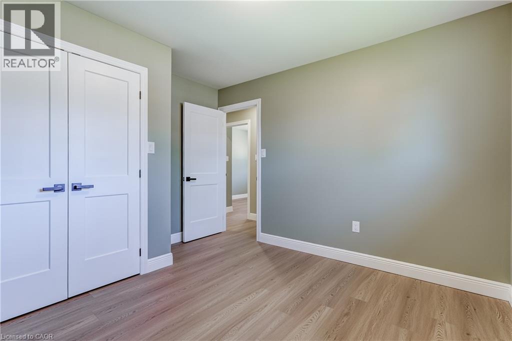Light wood-finish flooring complemented by white baseboards - 191 Glenmor Drive, Caledonia, ON - Indoor Photo Showing Other Room
