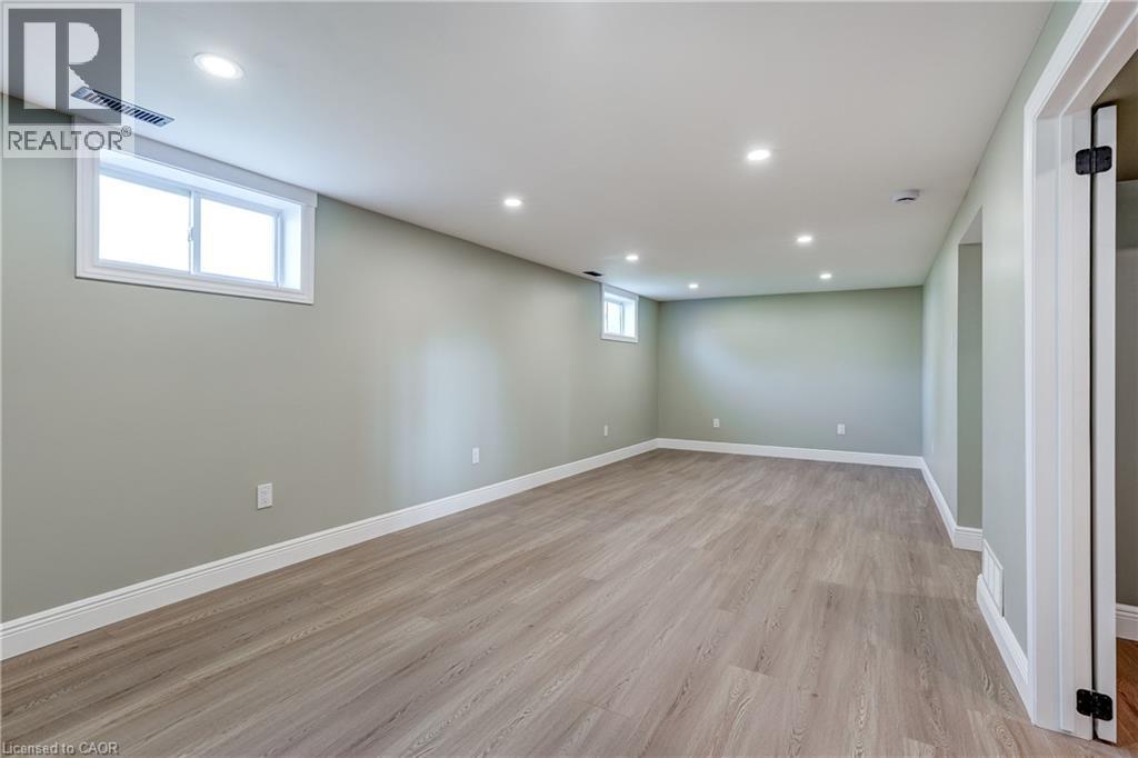 Spacious room featuring light wood-finish flooring, recessed lighting, and a neutral wall color - 191 Glenmor Drive, Caledonia, ON - Indoor