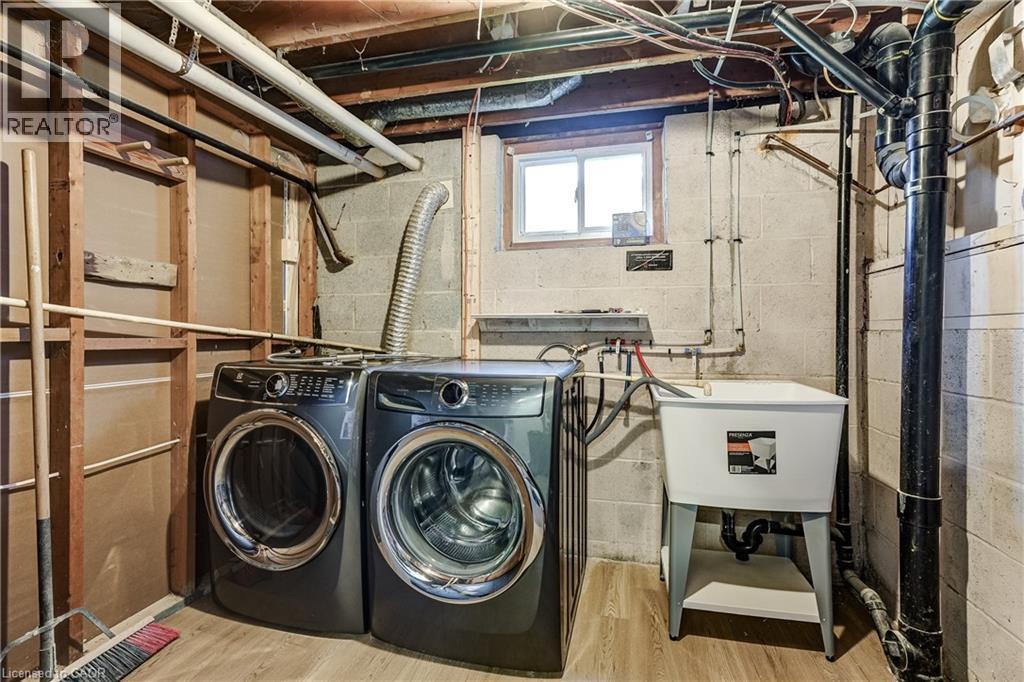 Laundry area featuring wood-finish flooring, a utility sink, and exposed block wall construction - 191 Glenmor Drive, Caledonia, ON - Indoor Photo Showing Laundry Room